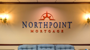 Custom dimensional acrylic lobby sign with raised logo and lettering installed in a Massachusetts business reception area by Northshore Custom Signs & Graphics.